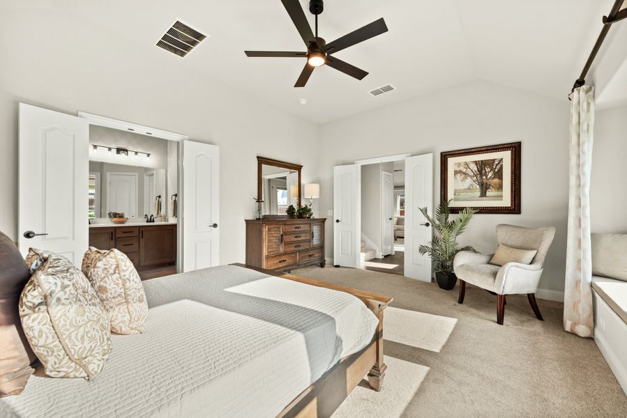 Master bedroom with ceiling fan, carpet flooring, seating area, and open ensuite bathroom with double vanity
