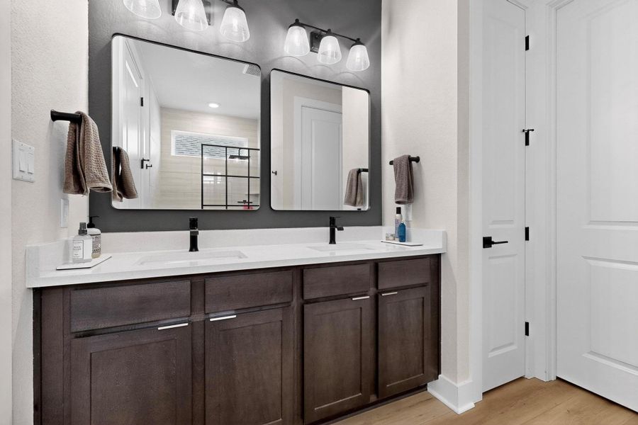Full bathroom with double vanity, a stall shower, and light wood-style flooring