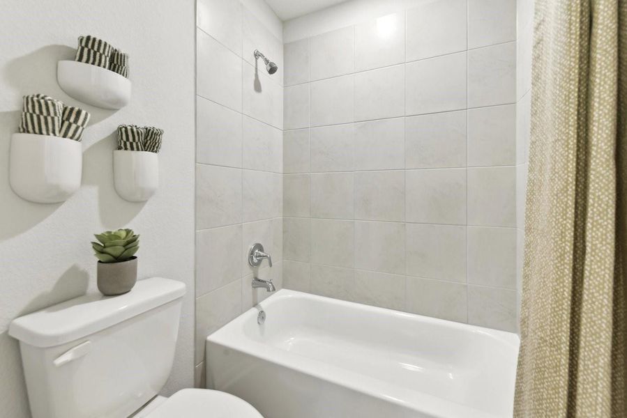 Crisp tiled walls surround a classic tub and shower combination.