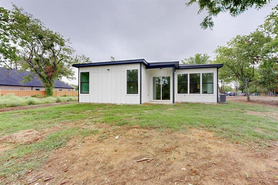 Modern white facade with black trim, featuring a flat roofline, multiple large windows, and a glass sliding door Modern white facade with black trim, featuring a flat roofline, multiple large windows, and a glass sliding door