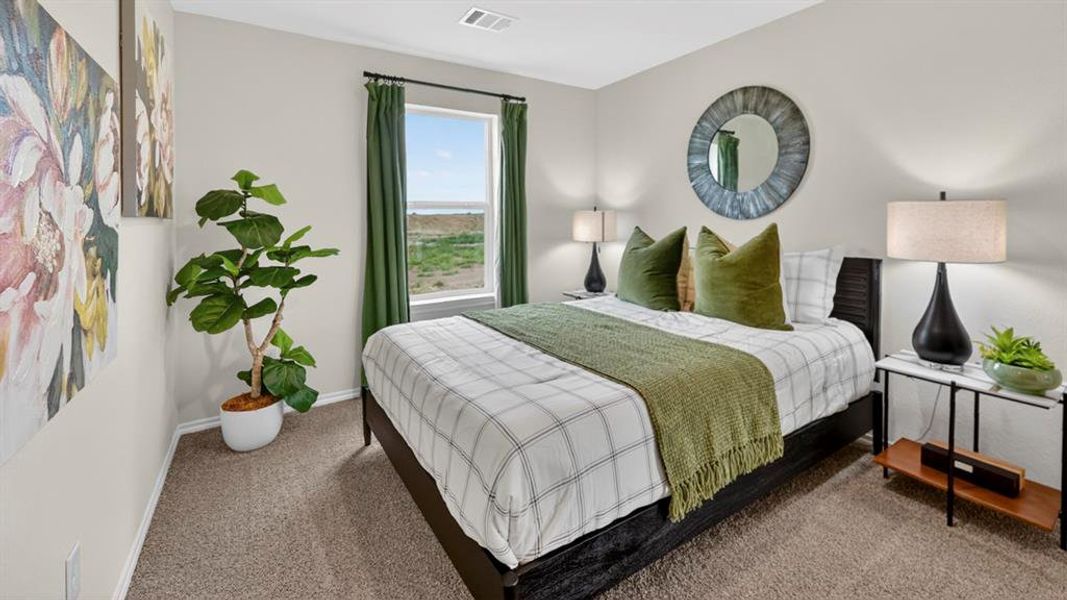 Spacious bedroom featuring neutral wall tones, carpeted flooring, a large window with green drapery, and a textured circular wall mirror Spacious bedroom featuring neutral wall tones, carpeted flooring, a large window with green drapery, and a textured circular wall mirror