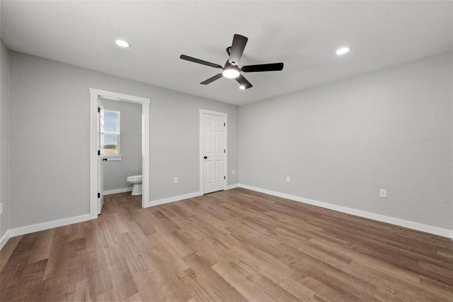 Unfurnished bedroom with wood finished floors, ensuite bathroom, recessed lighting, and a ceiling fan Unfurnished bedroom with wood finished floors, ensuite bathroom, recessed lighting, and a ceiling fan