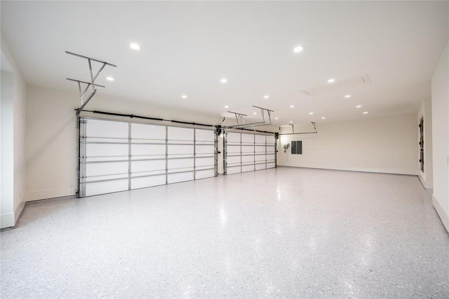 Spacious garage featuring two sectional garage doors, light gray epoxy flooring, recessed lighting, and crisp white walls