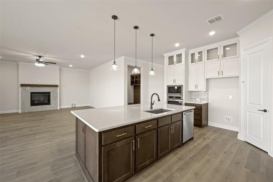 View of kitchen open to living area with decorative lighting and large island.