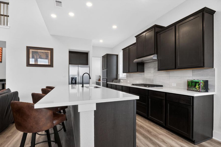 Modern kitchen featuring a large central island with a white countertop and undermount sink Modern kitchen featuring a large central island with a white countertop and undermount sink