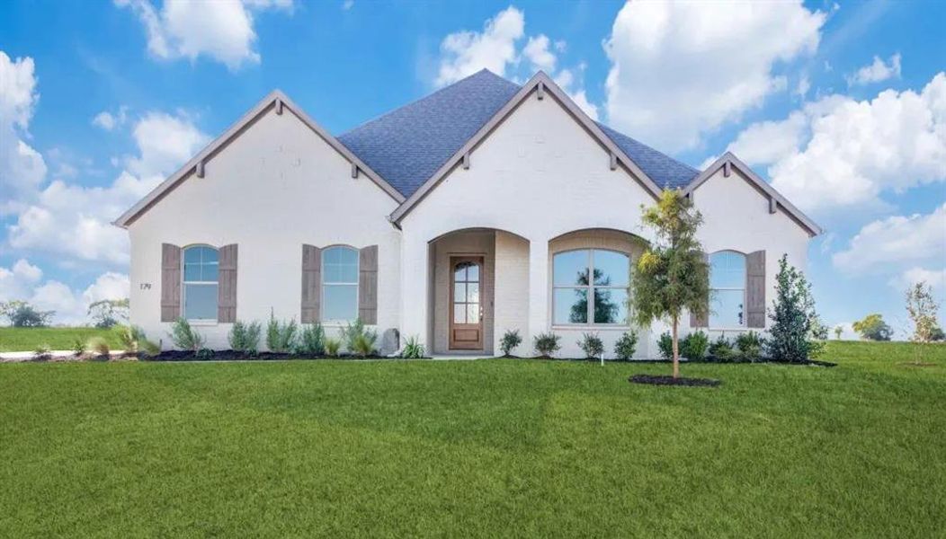 French country home featuring a front lawn, stucco siding, and a shingled roof