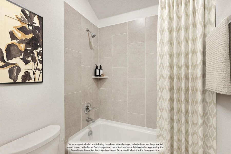 Bathroom with white soaking tub, large tile surround, built-in shelf, and patterned shower curtain