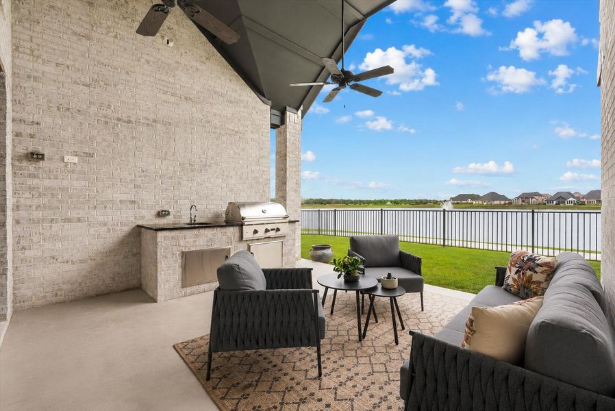 Spacious covered patio with an outdoor kitchen overlooking the water, perfect for relaxing or entertaining year-round.