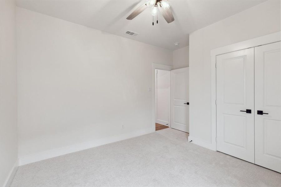 Unfurnished bedroom featuring light colored carpet, baseboards, visible vents, a ceiling fan, and a closet