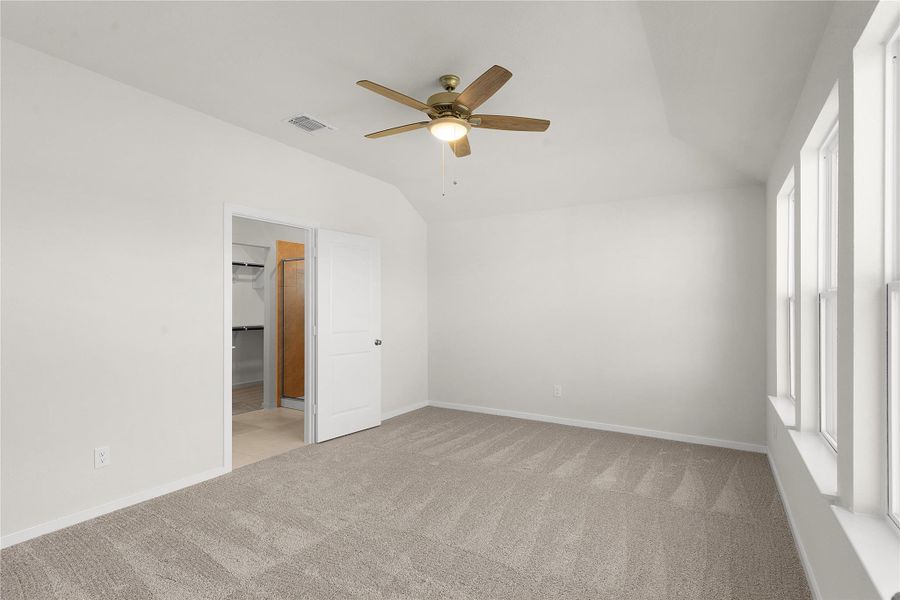 Unfurnished bedroom with vaulted ceiling, ceiling fan, and light carpet
