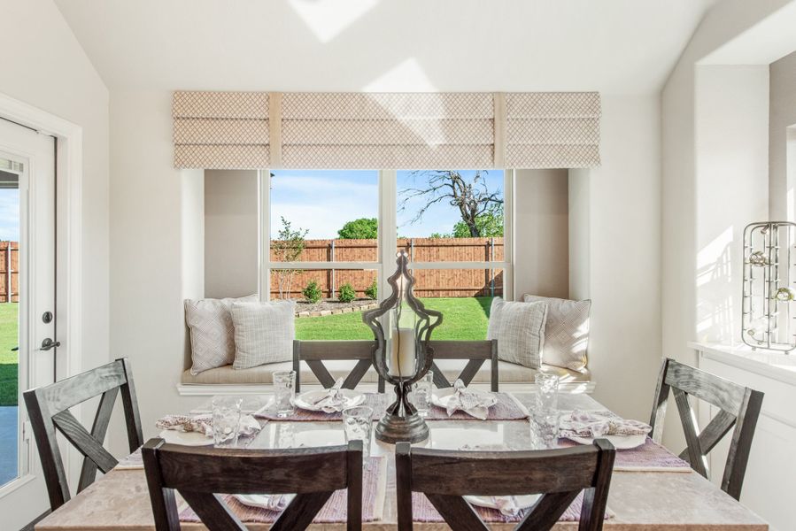 Dining area with wood table, window seat, and backyard view through double windows