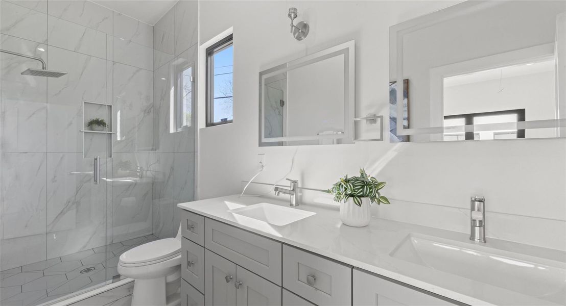 Bathroom with double vanity and a marble finish shower