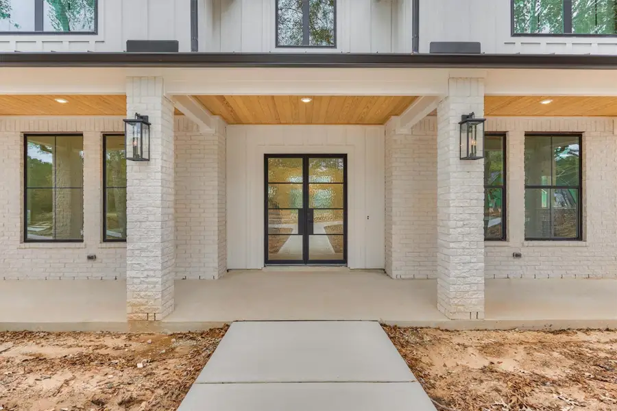 Sophisticated front entry featuring double glass doors, warm wood-accented ceiling, and clean modern brickwork for a polished welcome.