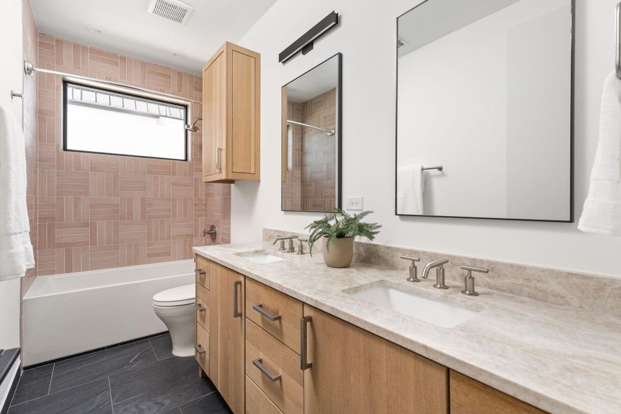Full bathroom featuring double vanity and shower / bath combination Full bathroom featuring double vanity and shower / bath combination