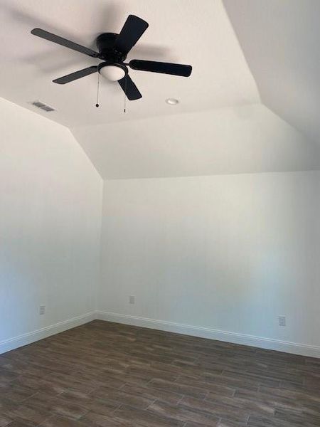 Additional living space featuring visible vents, baseboards, lofted ceiling, and dark wood finished floors