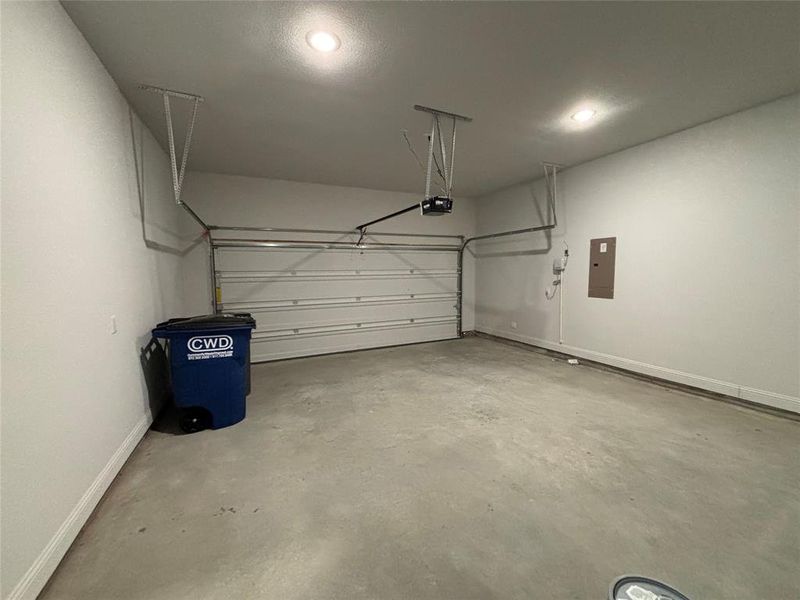 Garage featuring a garage door opener and electric panel