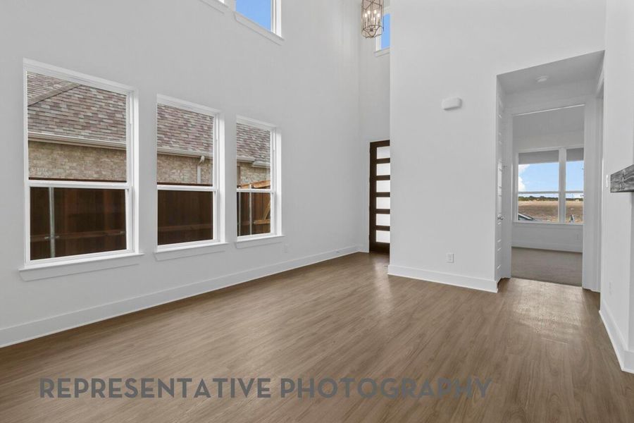 The welcoming entryway opens to a high-ceiling family room, featuring decorative balusters that overlook the upstairs game room, creating an airy and connected first impression.