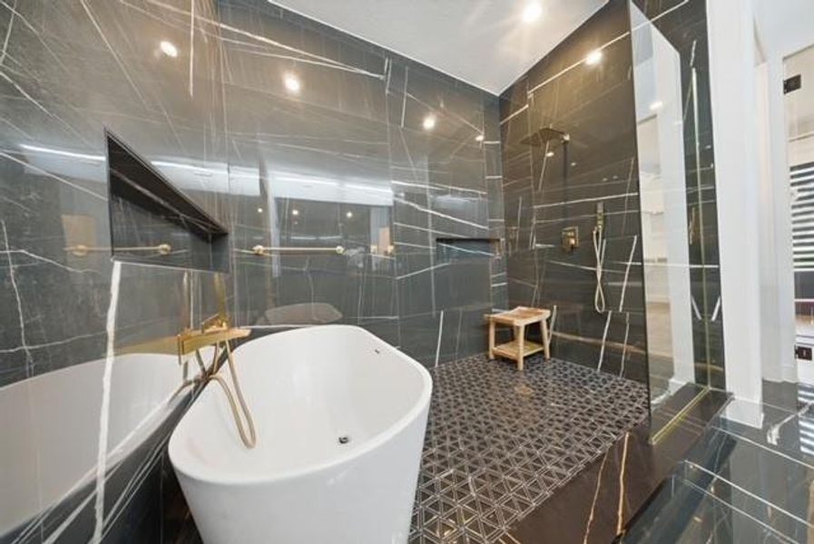 Sleek Primary bathroom featuring a freestanding soaking tub with gold-finish fixtures