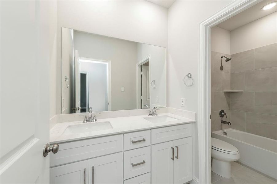 Bathroom with toilet, tile patterned flooring, double vanity, and bathtub / shower combination Bathroom with toilet, tile patterned flooring, double vanity, and bathtub / shower combination