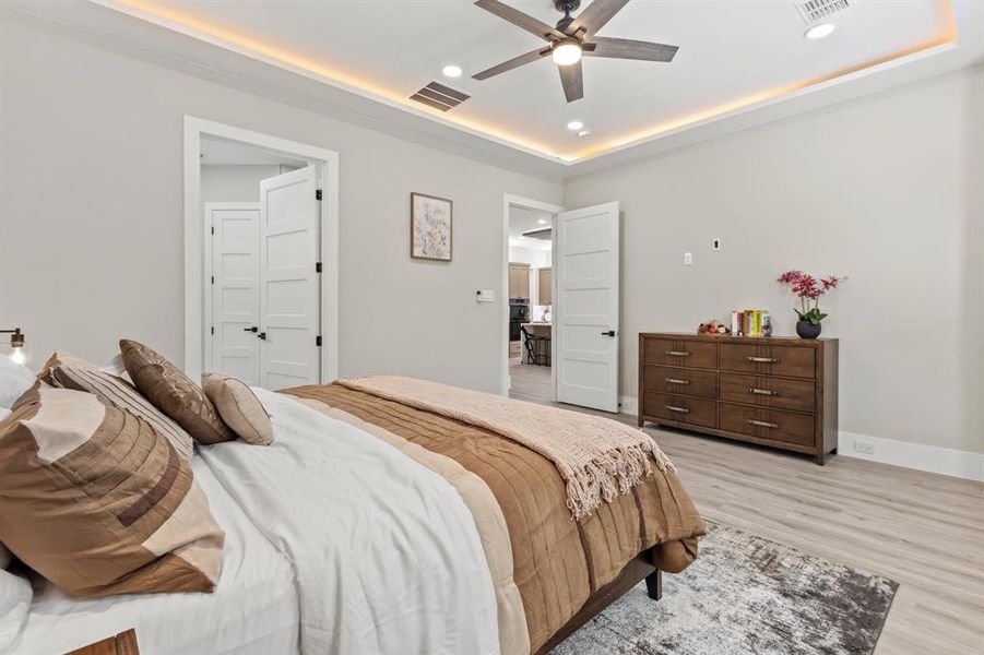 Bedroom featuring light wood-style floors, recessed lighting, a ceiling fan, and a tray ceiling