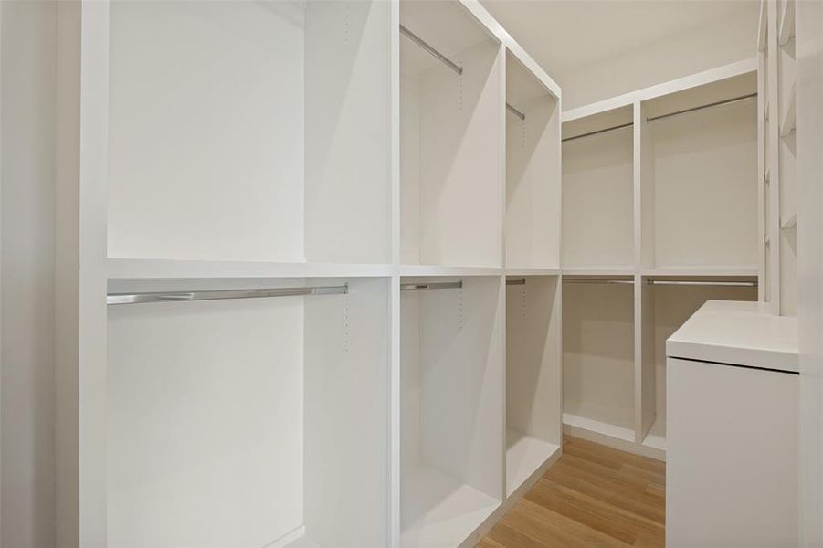 Generously sized primary closet featuring custom built-ins and organized storage solutions. Generously sized primary closet featuring custom built-ins and organized storage solutions.