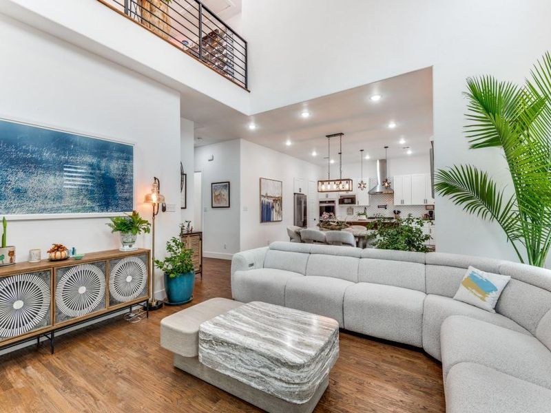 Living area with recessed lighting, wood finished floors, and a towering ceiling