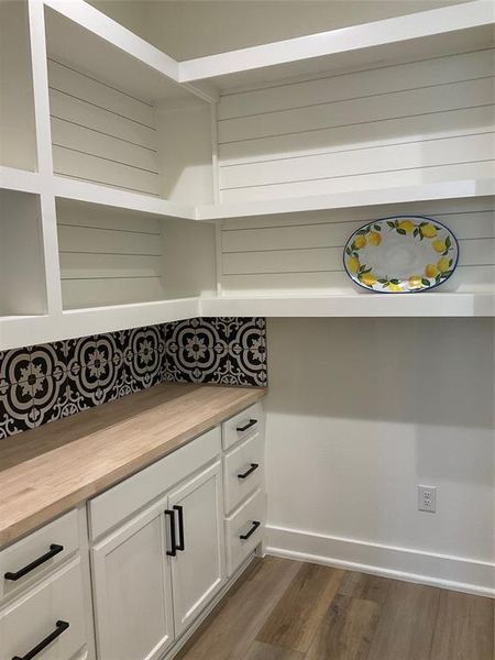 Custom walk in pantry with cabinets, drawers and butcher block counter tops, ship lap, and tile backsplash