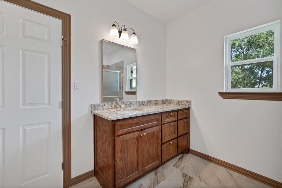 Bathroom featuring vanity, a stall shower, and light marble finish floors