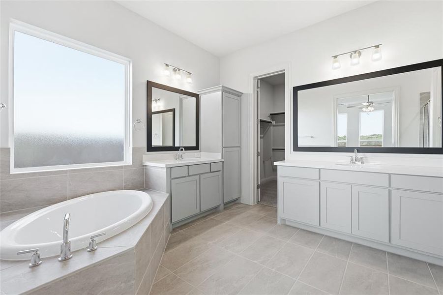 Full bath featuring plenty of natural light, two vanities, a garden tub, and light tile patterned flooring Full bath featuring plenty of natural light, two vanities, a garden tub, and light tile patterned flooring
