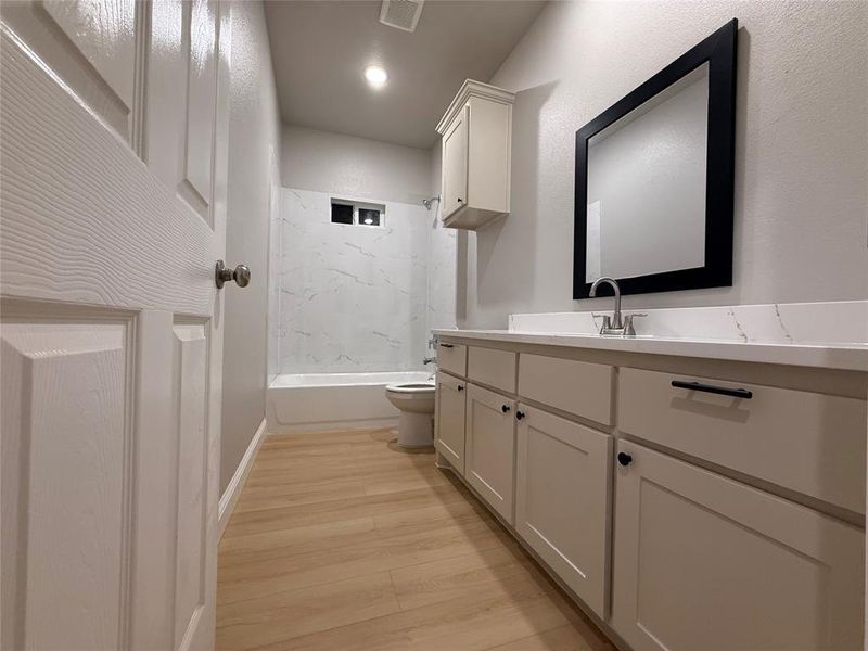 Bathroom with vanity, light wood-style floors, and shower / washtub combination