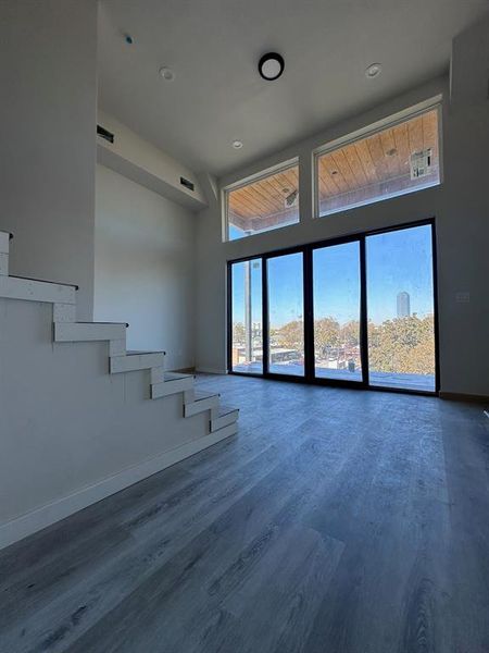 Unfurnished living room featuring a towering ceiling and hardwood / wood-style floors (laminate)