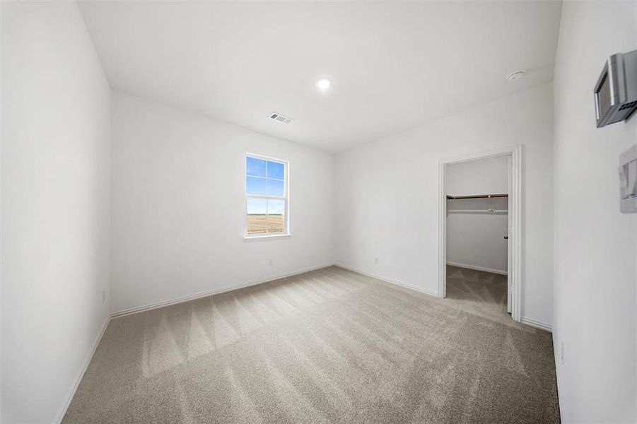 Unfurnished bedroom featuring light colored carpet and a spacious closet Unfurnished bedroom featuring light colored carpet and a spacious closet
