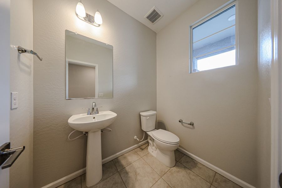 A bathroom with a sink toilet and mirror.