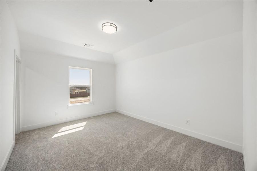 Unfurnished room featuring light carpet and lofted ceiling