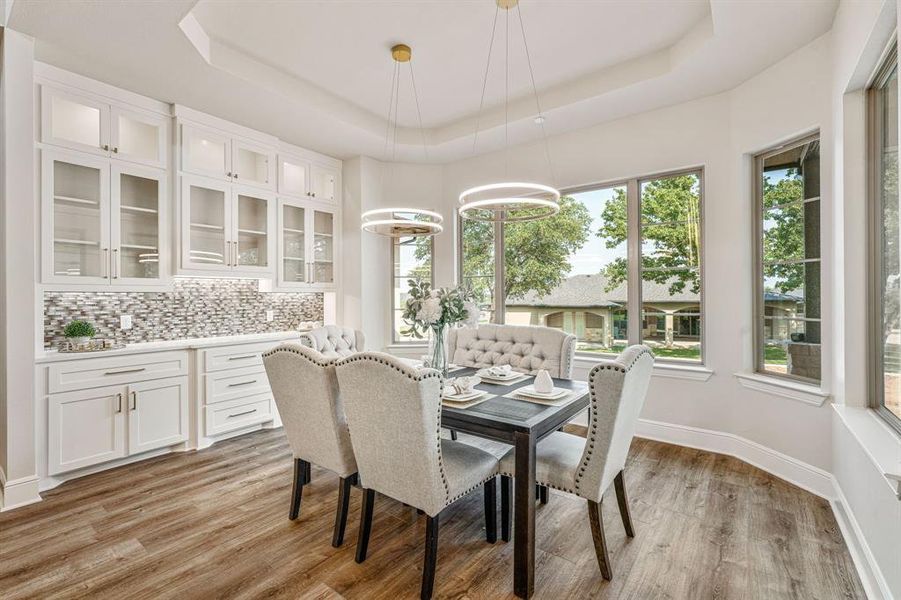 Dining space with light wood-type flooring and a tray ceiling