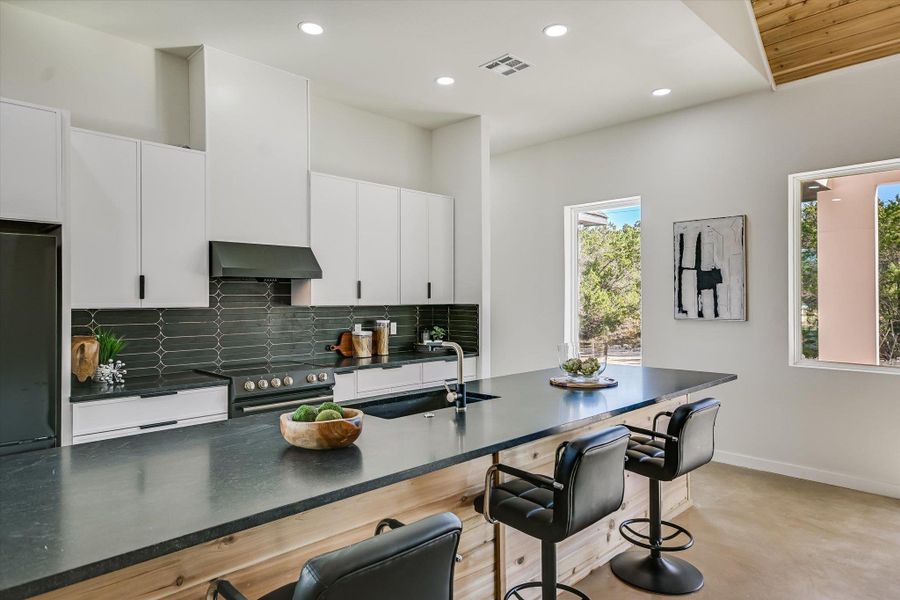 Kitchen featuring backsplash, a breakfast bar area, black electric range oven, recessed lighting, and white cabinets