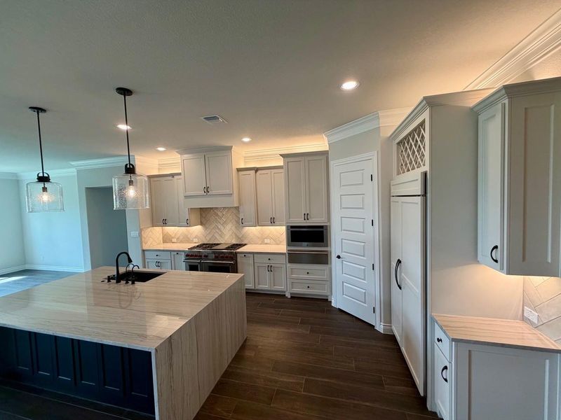 Rich wood floors contrast with elegant crown molding in this modern culinary space.