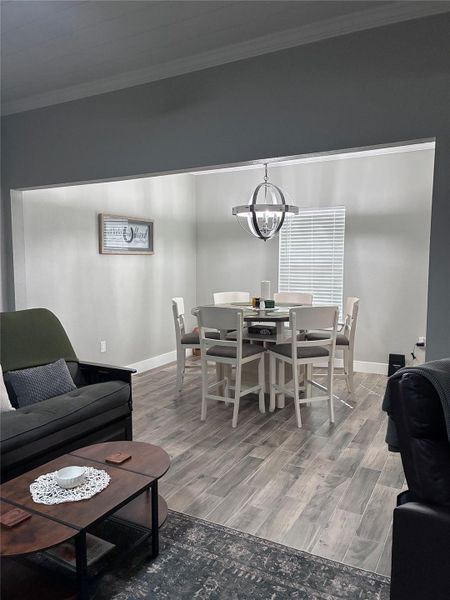 Dining area featuring ornamental molding, wood finished floors, and a chandelier