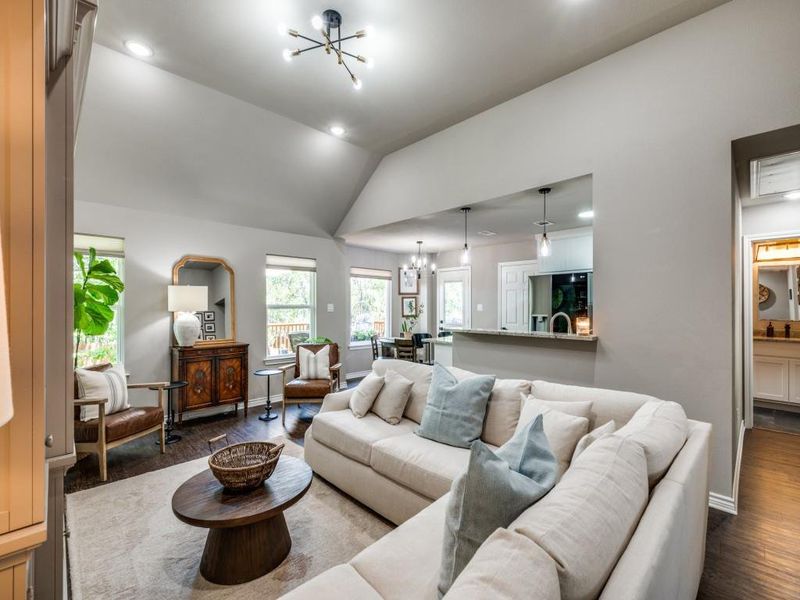 Living area featuring a chandelier, dark wood-style floors, vaulted ceiling, recessed lighting, and baseboards Living area featuring a chandelier, dark wood-style floors, vaulted ceiling, recessed lighting, and baseboards