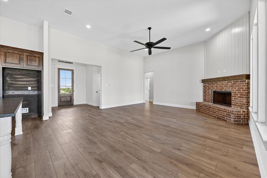 Unfurnished living room featuring a fireplace, dark wood finished floors, ceiling fan, recessed lighting, and a high ceiling
