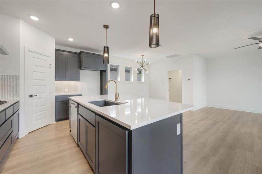Central kitchen island featuring a white countertop, undermount sink, and brass-finish faucet