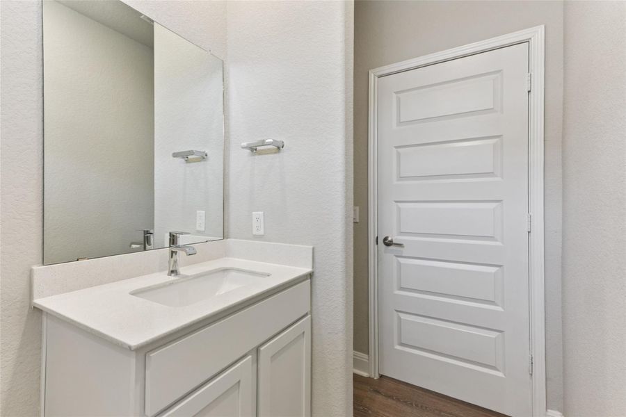 Bathroom with a textured wall, vanity, and wood finished floors Bathroom with a textured wall, vanity, and wood finished floors