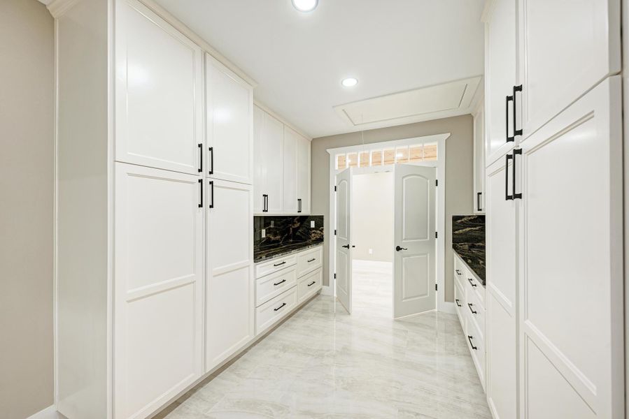 Gleaming stone tile floors anchor this well-appointed butler pantry with extensive custom built-in cabinetry. Gleaming stone tile floors anchor this well-appointed butler pantry with extensive custom built-in cabinetry.