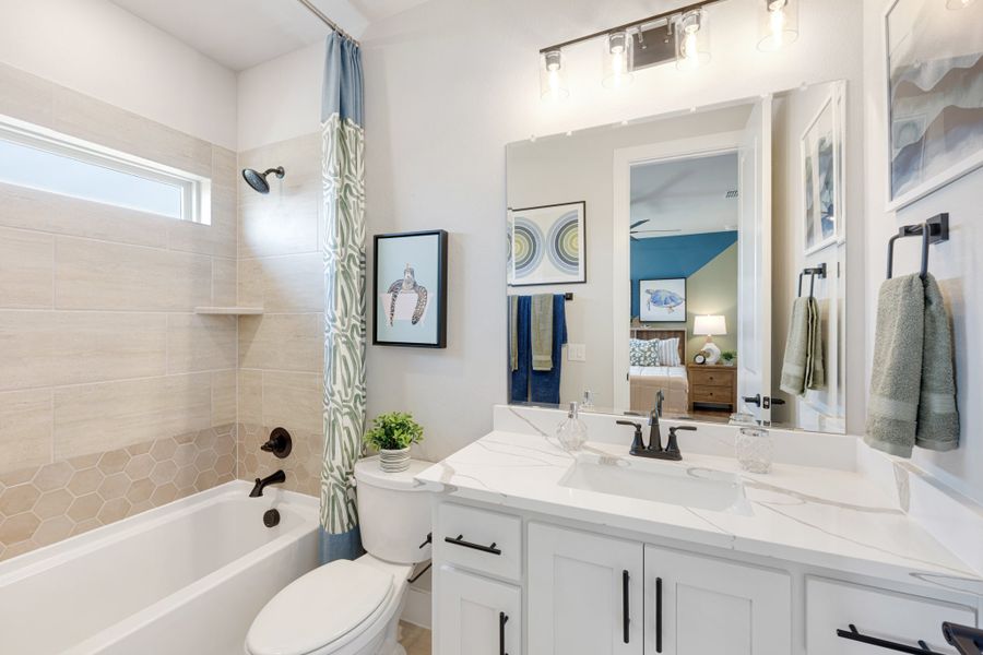 Bathroom with white vanity, quartz countertop, tiled tub-shower combo, and large mirror