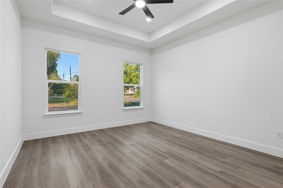 Spacious room featuring wood-finish flooring, crisp white walls, and a recessed ceiling with a contemporary ceiling fan