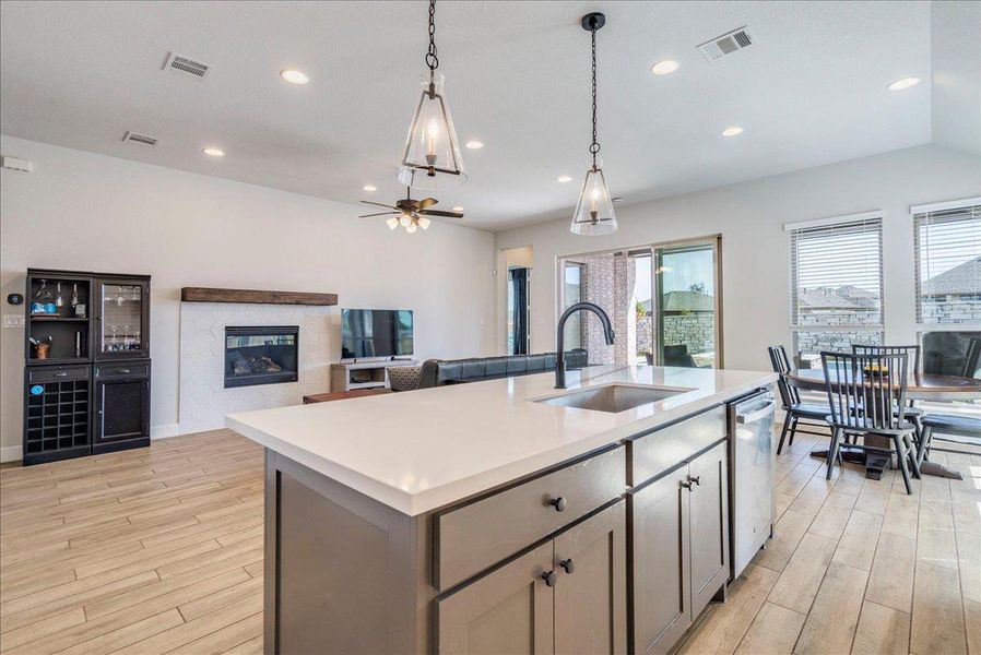 Kitchen featuring open floor plan, a kitchen island with sink, ceiling fan, and light wood-style flooring