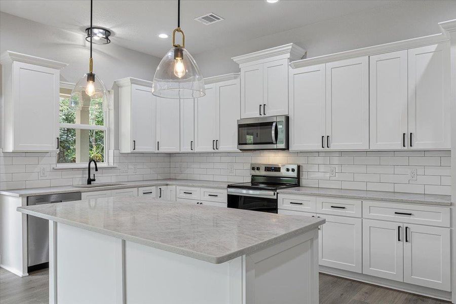 A well-appointed kitchen features a central island, subway tile backsplash, and a suite of modern appliances. A well-appointed kitchen features a central island, subway tile backsplash, and a suite of modern appliances.