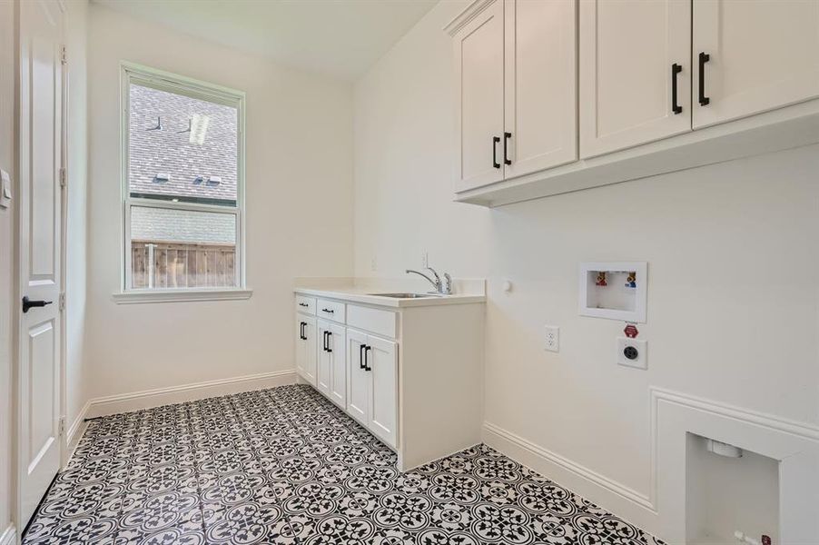 Clothes washing area featuring cabinets, a healthy amount of sunlight, hookup for an electric dryer, and light tile patterned floors