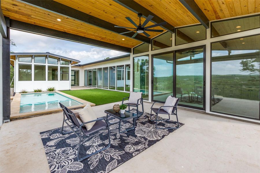 An inviting outdoor living space features a covered patio, refreshing pool, and scenic views.