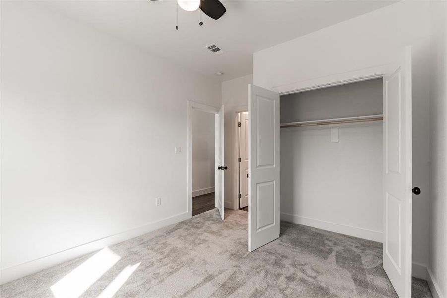 Unfurnished bedroom featuring ceiling fan, a closet, and light carpet